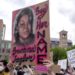 Outside, protest signs are hoisted in the air. The front-most sign reads, "Say Her Name, Breona Taylor." A spray painted image of Breona Taylor, a young Black woman with brown skin and straightened hair appears next to the text. 