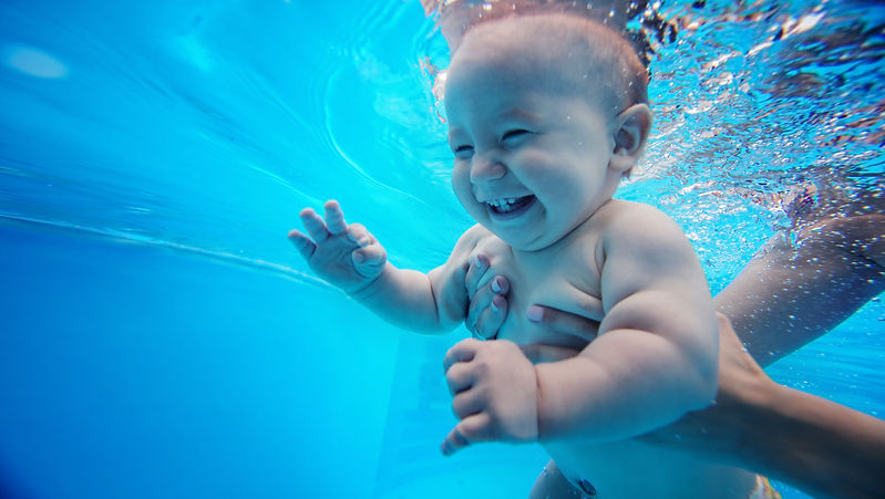 Baby background. Happy infant learn to swim, dive underwater with fun in pool to keep fit.
