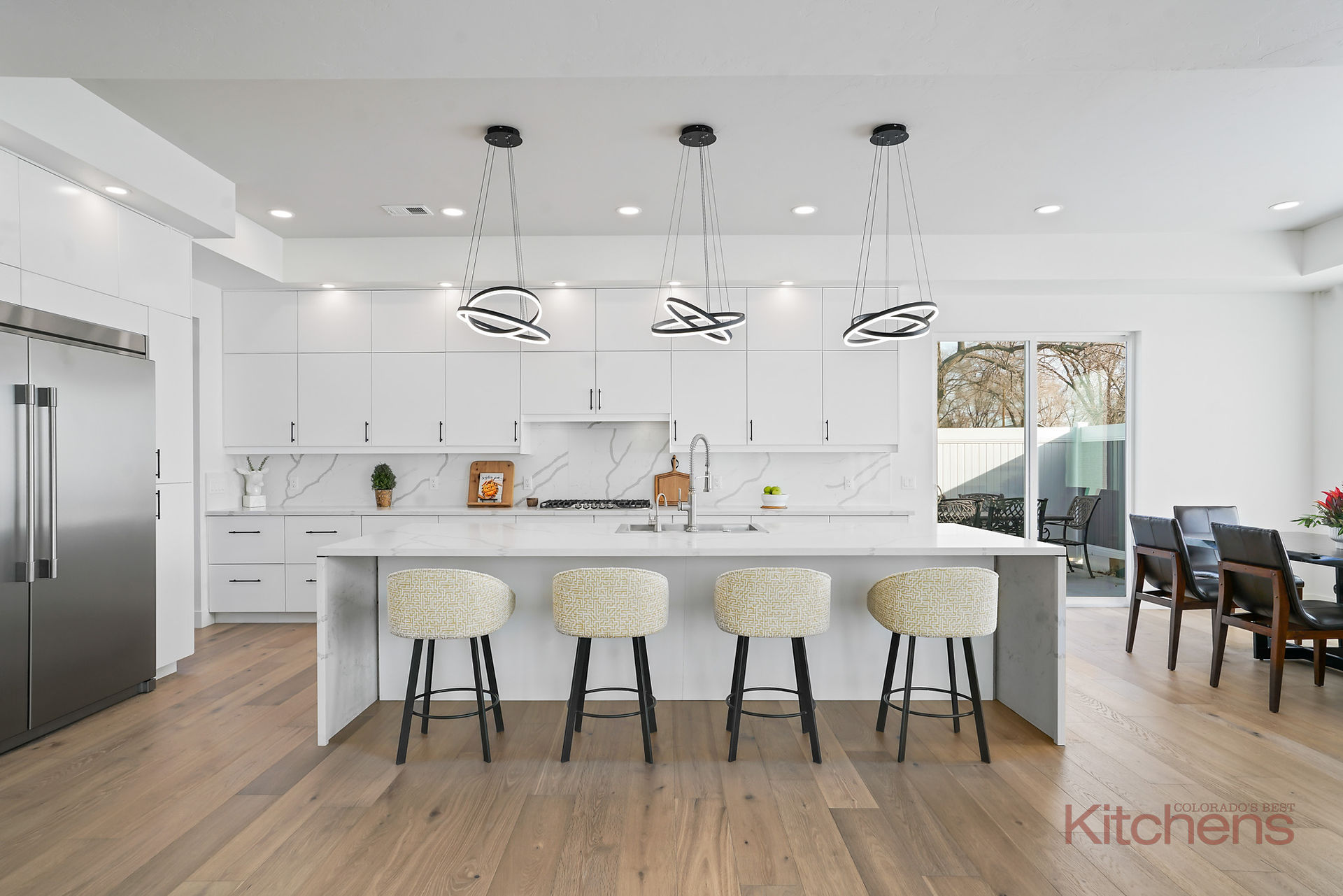 modern white kitchen with pendant lights and stools at the island