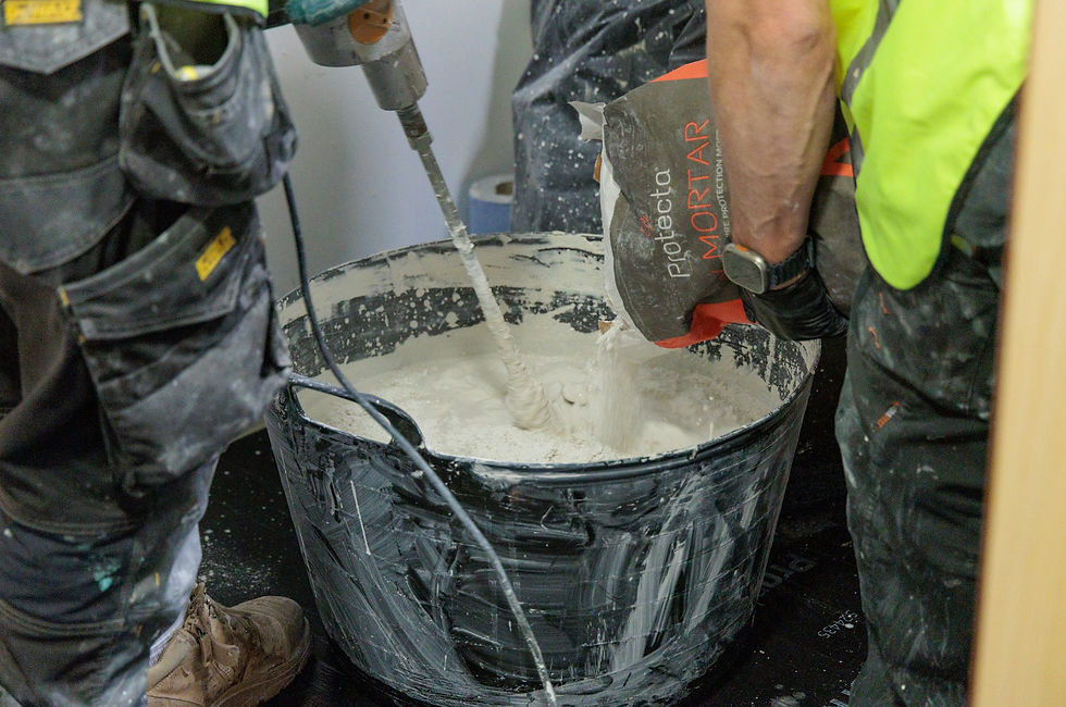 Ecosafe’s fire stoppers mixing Protecta fire-resistant mortar in a large tub for compartmentation installation.