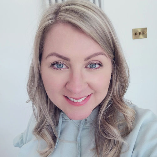 An image of a blonde lady in her 30's smiling in a sage green hoody