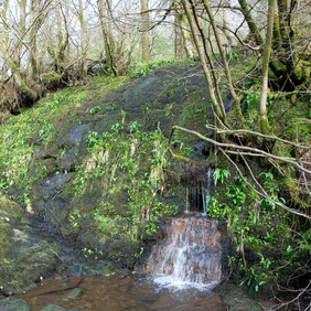 The Black dam stone embankment holding back the water with the outflow from the sluice discharging water.