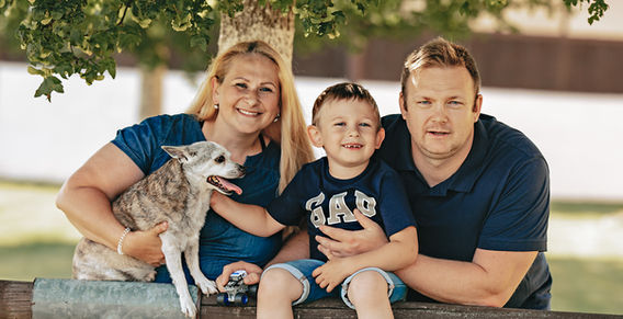 Usísměvavá rodina s malým psem a synem pózuje na slunci. Rodinné