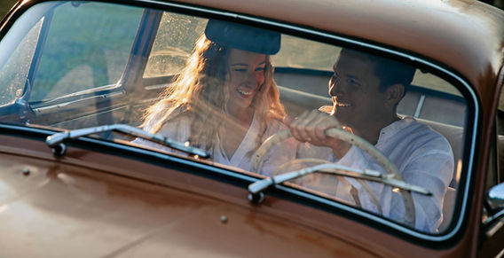 Usměvavý pár v hnědém autě, radostný výlet. Od rande k zásnubám. Sluneční světlo.