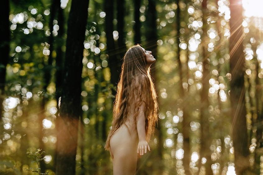 Žena s dlouhými vlasy v lese, boudoir a akty ženy, sluneční záře v pozadí.
