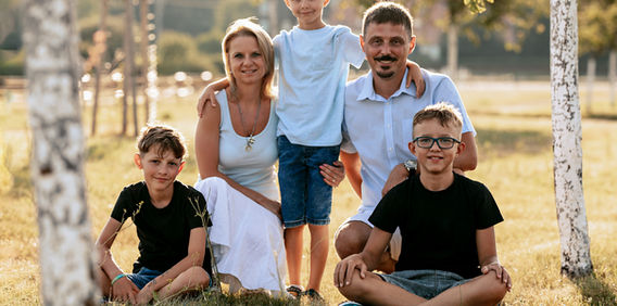 Usměvavá rodina pěti osob pózuje pro fotografii v parku Rodinné  slunečného dne.