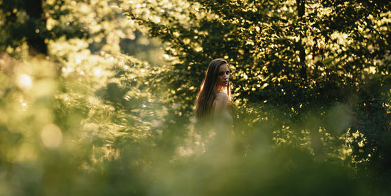 Žena v přírodě mezi zelenými listy, sluneční světlo, Boudoir a akty ženy.