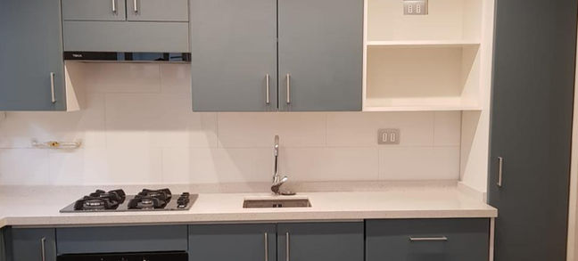 Cocina fabricada con cubiertas de cuarzo blanco y desfondado para lavaplatos pequeño y puertas postformadas radio 8 color Mist 2251 mate con gabinete bajo o dispensero para almacenar articulos de aseo instaladas por Topmobili.