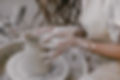 Young beautiful woman with long curly hair in white apron creating handmade ceramic bowl i