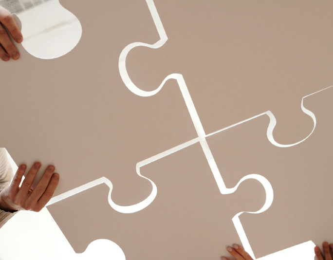 oopération et co-construction en teambuilding –Mains assemblant de grandes pièces de puzzle symbolisant la coopération, la communication et la co-construction d’un projet d’équipe lors d’un teambuilding animé par Martine Galland à Lausanne.