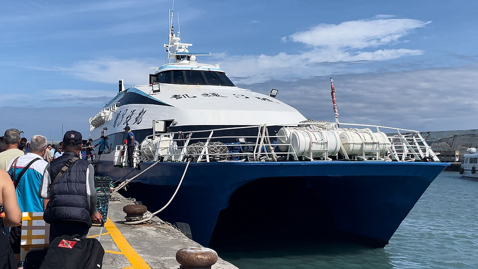 A large modern ferry. Passengers queue to board to the left