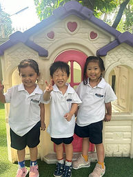 Three Storytime Preschool children smiling near playhouse