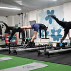 Three people on Pilates reformers