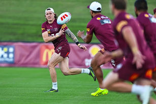 Rugby player Kurt Mann donning the Maroon uniform passing the footy on field to teammates nearby.