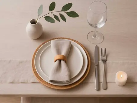 Uma mesa posta minimalista com elementos assimétricos e iluminação natural.