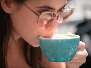 Um close em câmera lenta de uma taça ou xícara no instante em que toca os lábios de alguém.