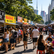 Imagem editorial ampla de uma feira gastronômica de rua em São Paulo, com barracas coloridas, pessoas circulando, alimentos sendo preparados na hora e a atmosfera vibrante de um domingo ensolarado próximo à Avenida Paulista