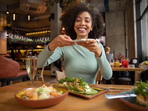 Mulher tirando foto do prato no restaurante