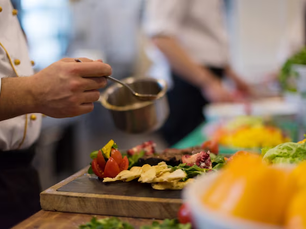 Chef finalizando um prato em ambiente festivo, com luz baixa e clima de bastidores.