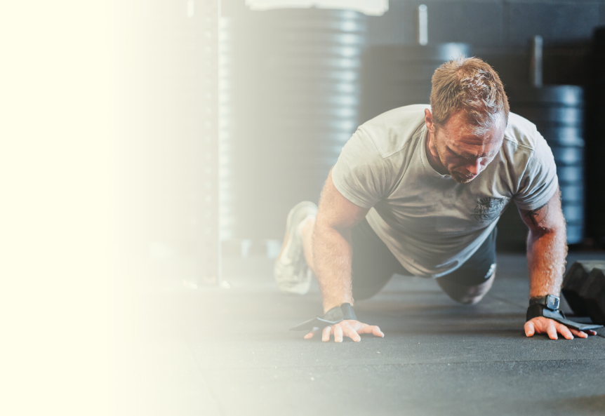 Banner image showing a guy doing a burpee in a class at Rockhouse CrossFit
