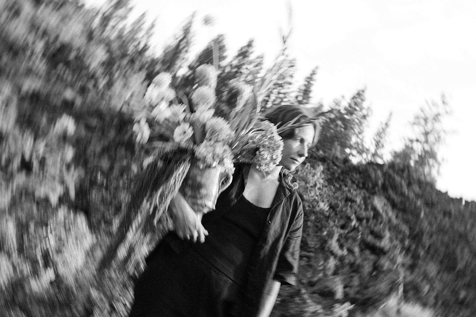 Blurred black-and-white photo of a woman carrying a large textural bouquet