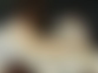 흰 침대에 누워 정면을 바라보는 여성과 꽃다발을 든 여성, 발치에서 꼬리를 세운 검은 고양이