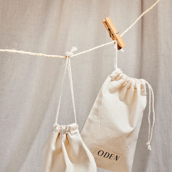 Pochons coton siglés Oden, utilisés pour les envois produits – stylisme produit sur fond neutre.