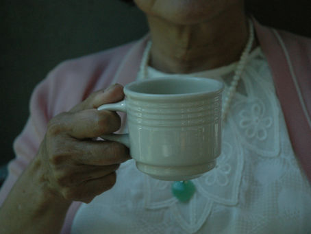 A hand of an old lady holding a white mug. This portrays Shien Dewani's story of Brenda.