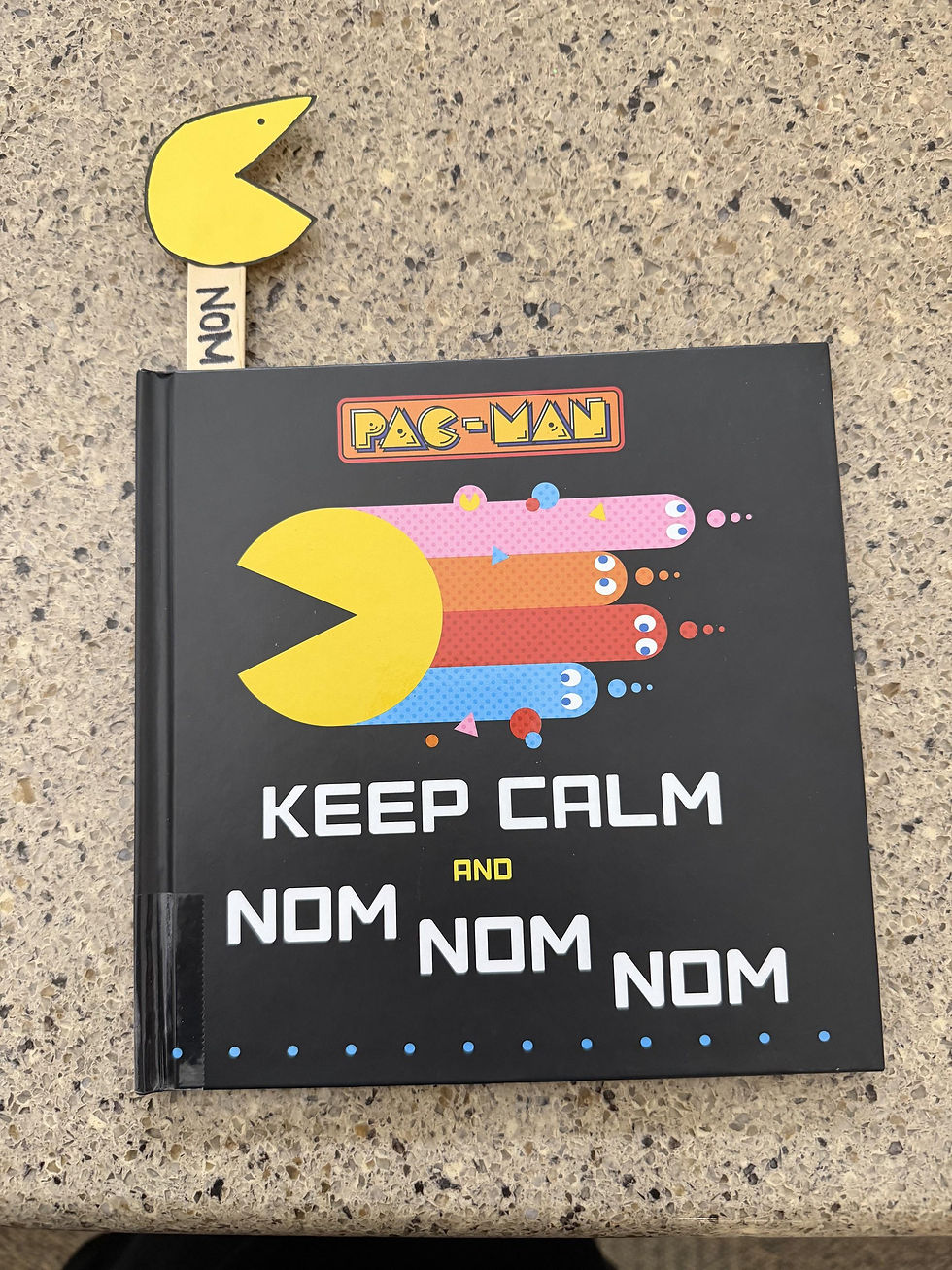 The book shows pac man zooming away with four colorful ghosts trailing behind. The bookmark craft is poking out the top.