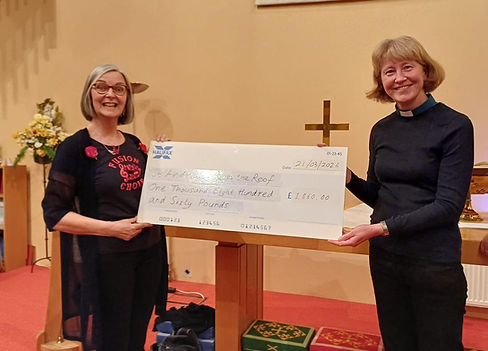 Two smiling people holding a large fundraising cheque for £1,860