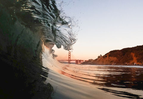Featured image of Chef's Kiss image of wave lip just touching the tip of the golden gate bridge in glassy, sunset conditions.