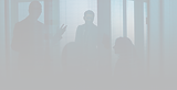Silhouettes of professionals in a dark office meeting.