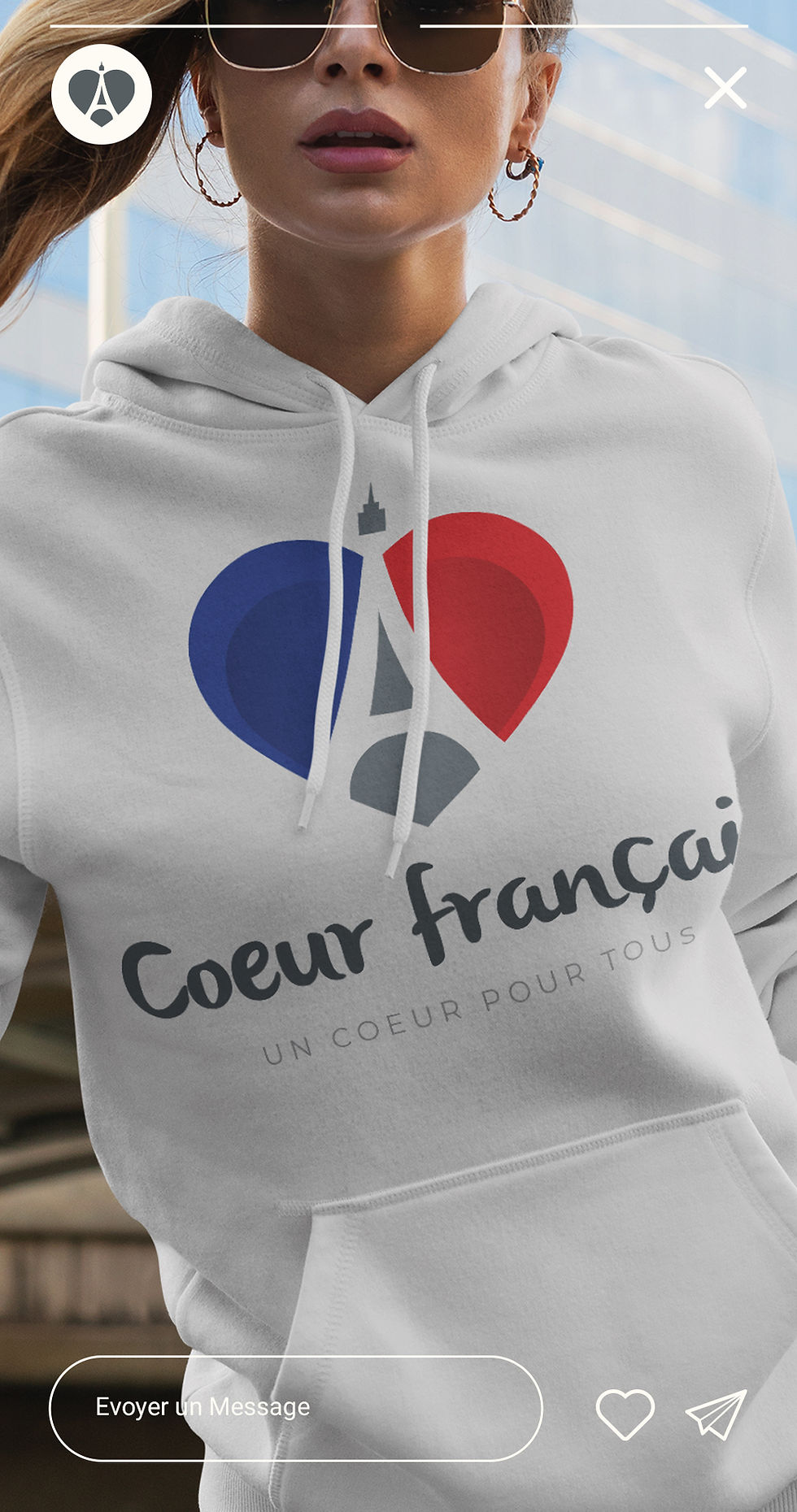 Une femme portant un sweat à capuche blanc avec le logo d'un coer bleu, blanc et rouge avec la tour eiffel au mileu.