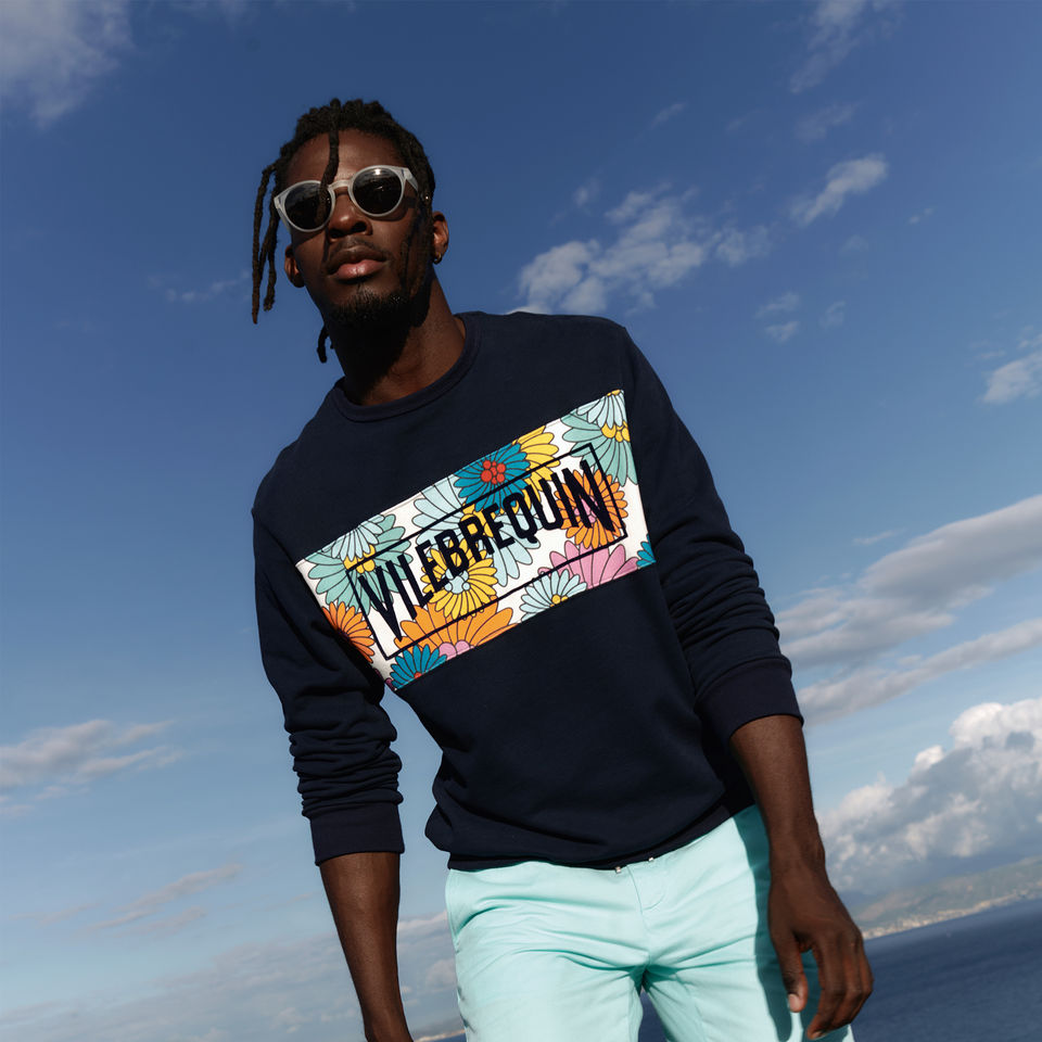 Un homme noir marchand au bord de la plage avec un pule Vilebrequin.