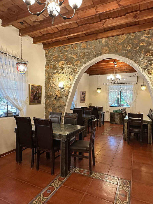 פנים מסעדת בית שלום – קשת אבן, שולחנות עץ ותאורה חמה בבית היסטורי במטולה העתיקה