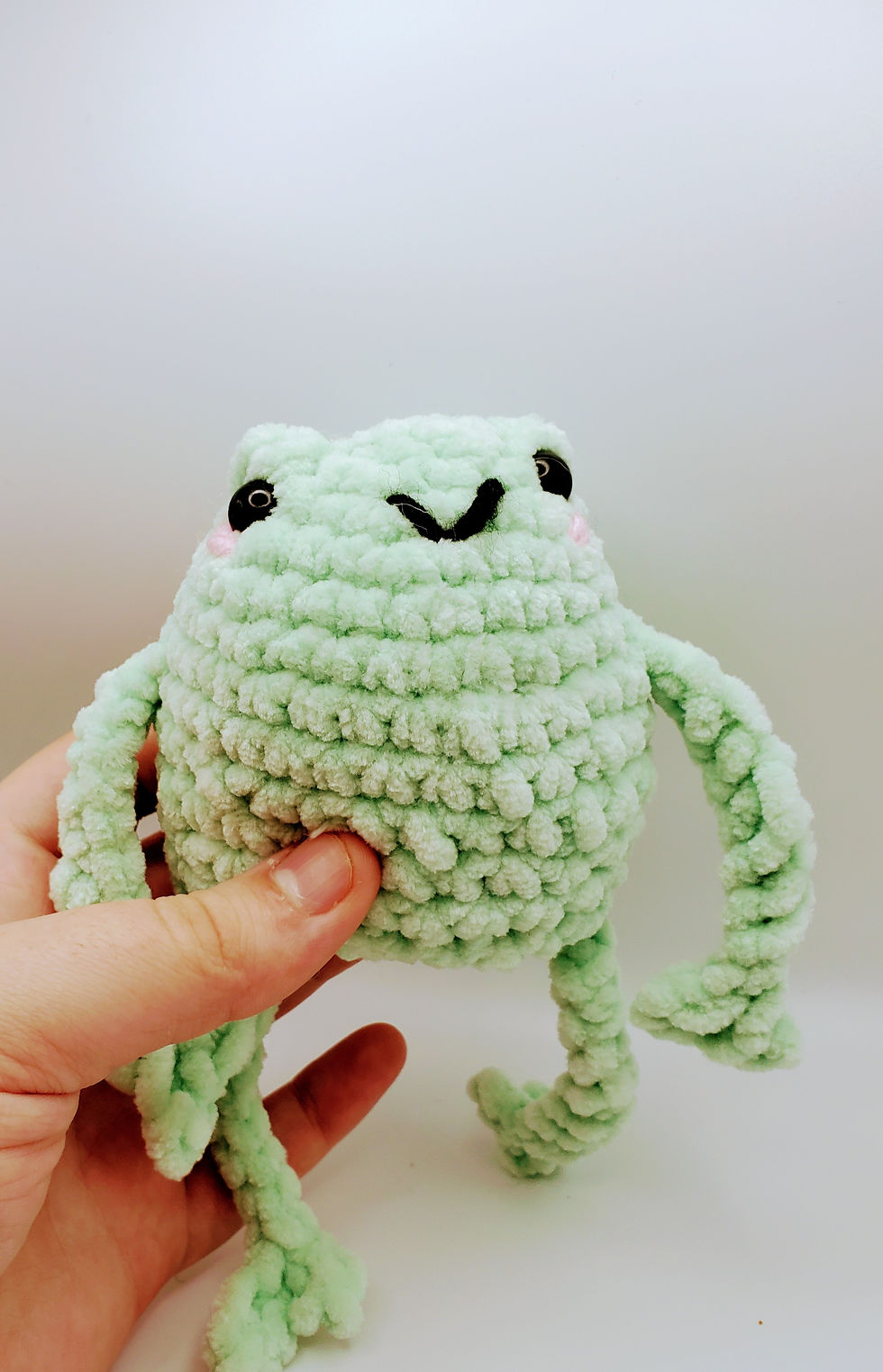 Thumbnail: mint green leggy frog being held by a tan hand