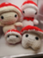 Group of four mushrooms of different sizes. All are write and have red caps with white spots.