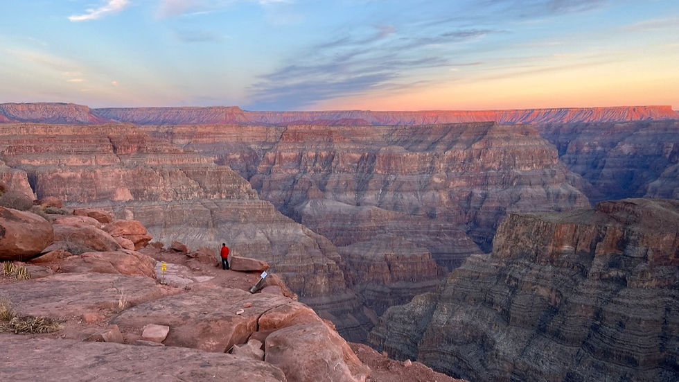 Grand Canyon Facts; a man stands at the edge of the western rim of the Grand Canyon overlooking an expansive view with no guardrails. ©AshleyOnozWright for Manifesting Travel