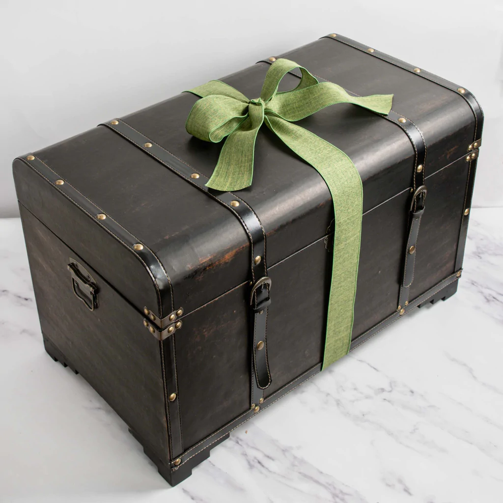 A brown trravel trunk with leather straps and metal hardware, wrapped in a green gift bow and featured on gift ideas for foodies who love travel on Manifesting Travel