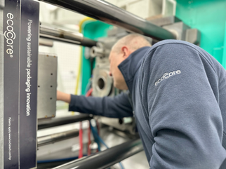 Man leaning into an injection moulding machine to adjust the wear plates