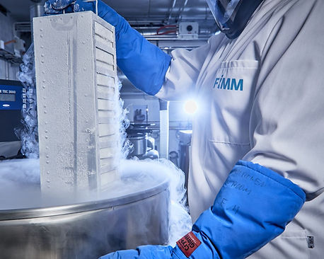 Laboratoriotyöntekijä nostaa näytelaatikoita nestemäisestä typestä, josta nousee höyryä