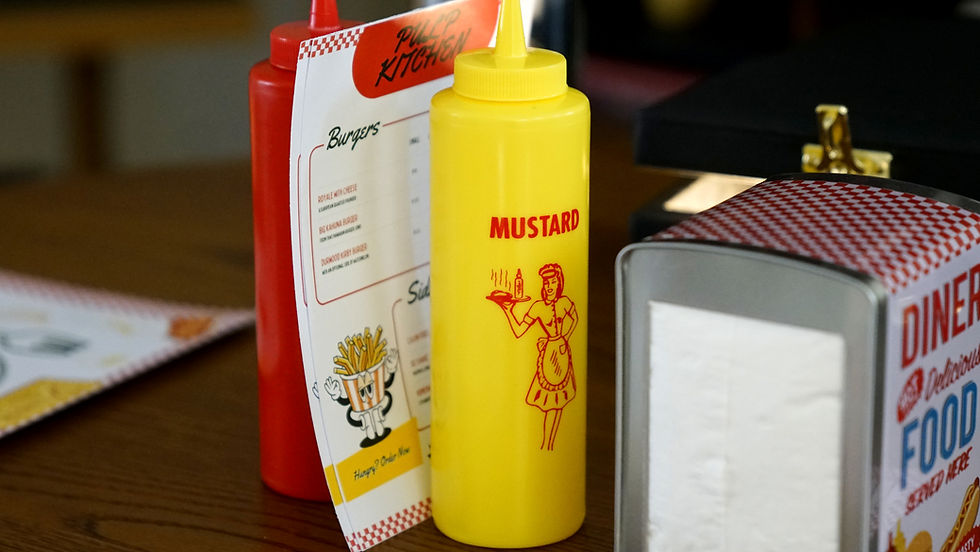 Yellow mustard bottle, red ketchup bottle, and a menu on a diner table. "Pulp Kitchen" and "DINER" text visible. Retro design.