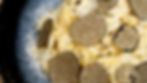 Christmas Fettuccine from The Holiday. Close-up of creamy pasta topped with thin black truffle slices, on a dark plate. Parmesan cheese is sprinkled on top, creating a gourmet look.