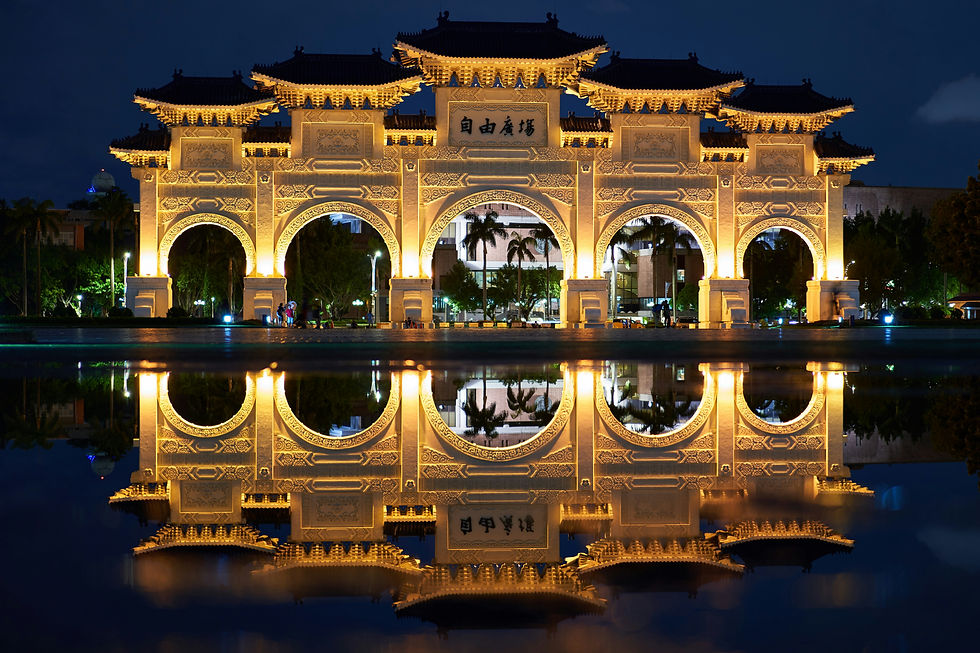 Illuminated archway at night with intricate patterns, reflected in water. Text in center. Trees and buildings in background create a serene mood.