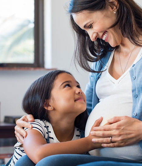 Pregnant mom and daughter smiling and hugging