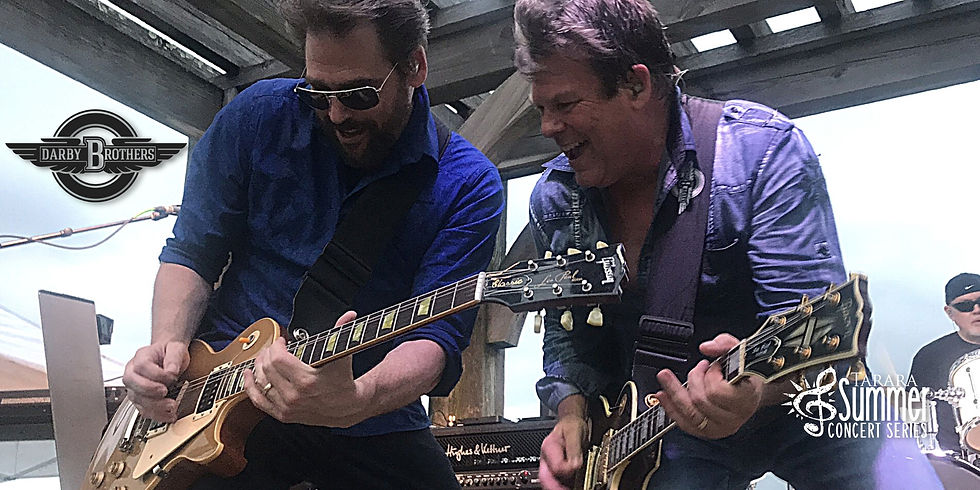 Two men playing guitars on stage.