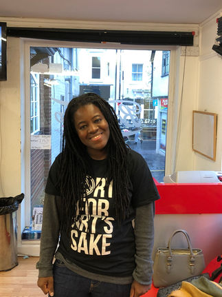Woman with long dreadlocks in a barber shop, smiling at the camera