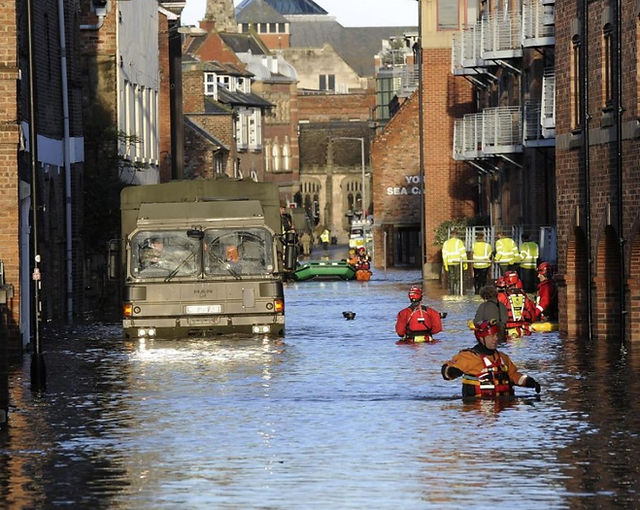 Army personnel wading down a flooded street