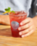 A hand holding a cup of Erva’s yerba mate blend on a wooden base.