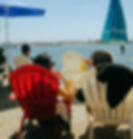 Two people seated by the beach in summer, enjoying chilled yerba mate drinks.